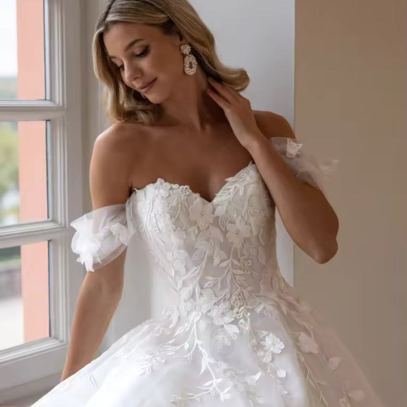 Off-shoulder lace wedding dress with floral appliqué bodice and layered tulle skirt