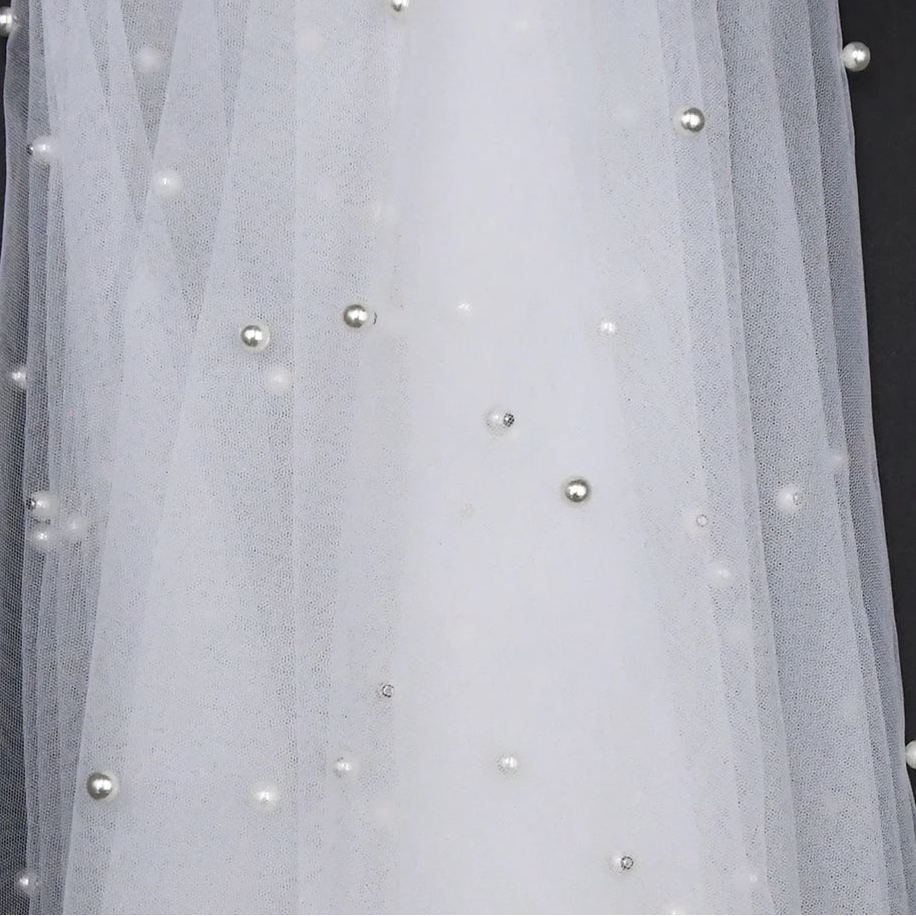 Sheer bridal cape with small pearl beads scattered across the tulle panel