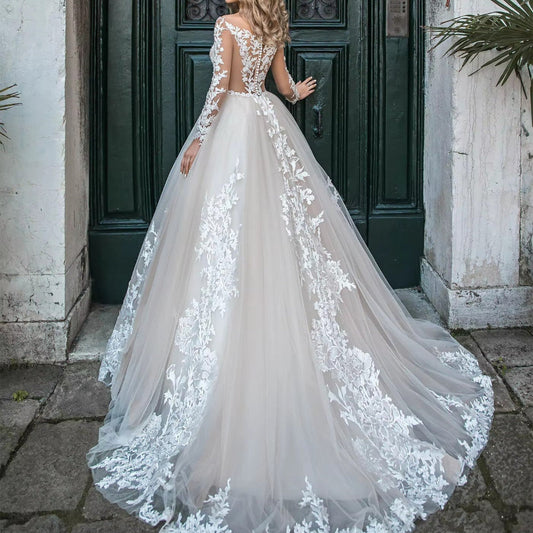 Back view white tulle wedding dress with lace appliqué long sleeves and flowing A-line skirt