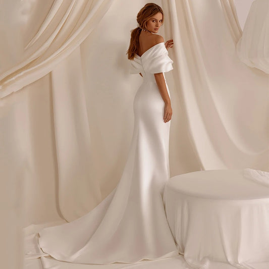 White satin mermaid wedding dress with off-shoulder neckline and flowing train
