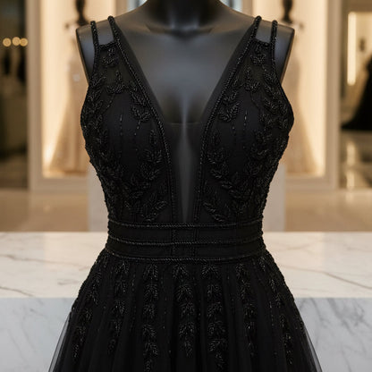 Black evening dress bodice close-up with sheer mesh straps, lace detailing, V neckline