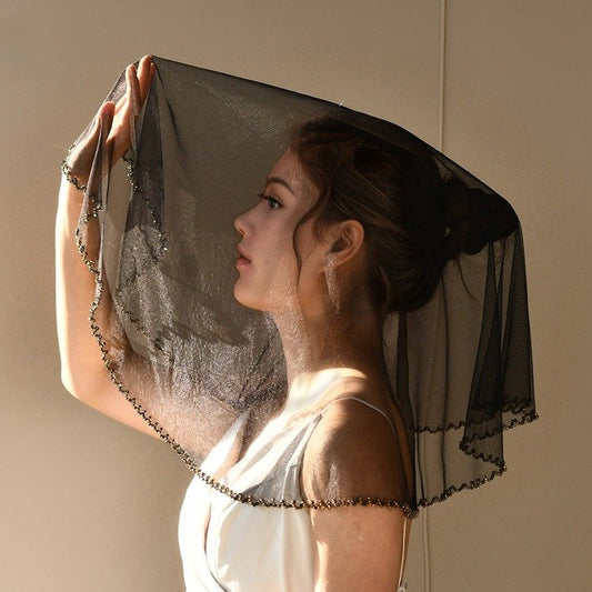 Black short bridal veil head cover with beaded trim, draped over head and shoulders