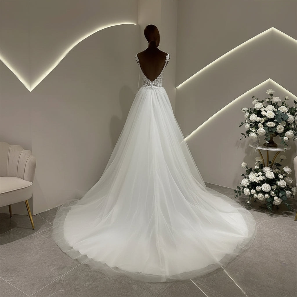 Ivory A-line wedding dress with lace bodice and flowing tulle skirt, rear view on mannequin
