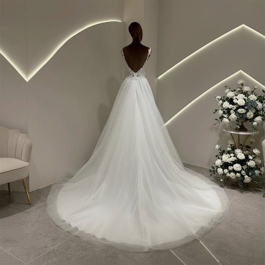 Ivory A-line wedding dress with lace bodice and flowing tulle skirt, rear view on mannequin