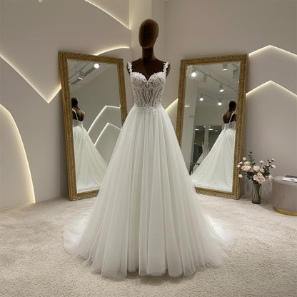 Ivory A-line wedding dress with off-shoulder lace details and layered tulle skirt