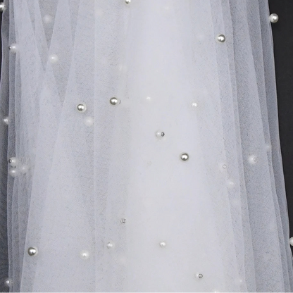 Sheer bridal cape with small pearl beads scattered across the tulle panel