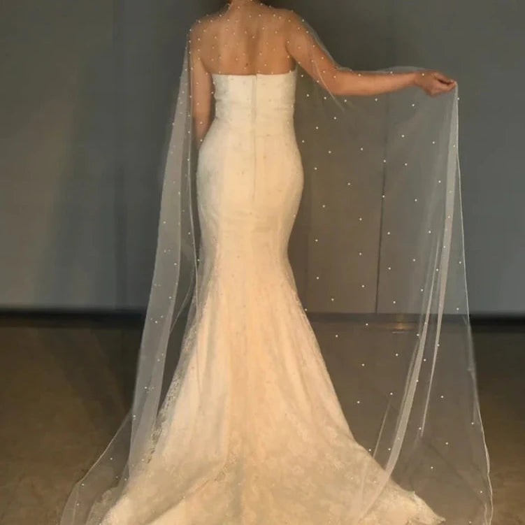 Ivory bridal cape shawl draped over shoulders with scattered pearl bead details