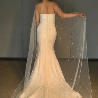 Ivory bridal cape shawl draped over shoulders with scattered pearl bead details