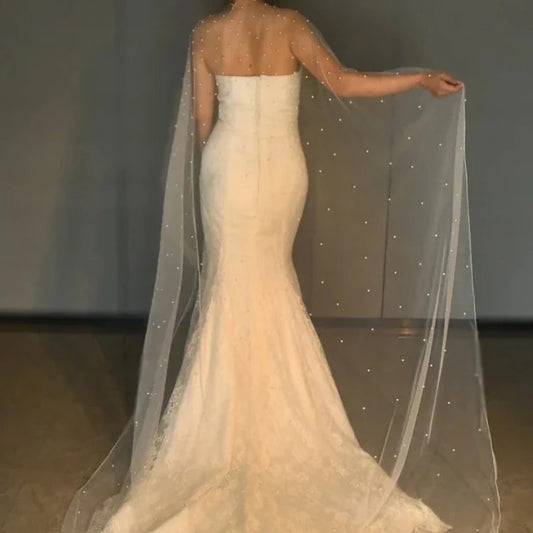 Ivory bridal cape shawl draped over shoulders with scattered pearl bead details