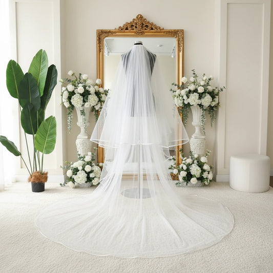 White cathedral-length bridal veil with layered tulle and satin-trim finish on model