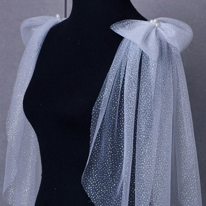 White wedding dress with pearl shoulder bow and long sheer glitter cape sleeves