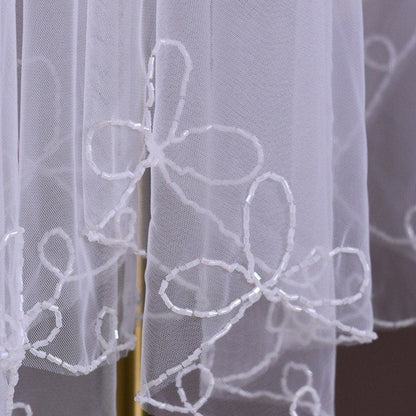 Sheer tulle veil panel with white floral embroidery and bead-like detail