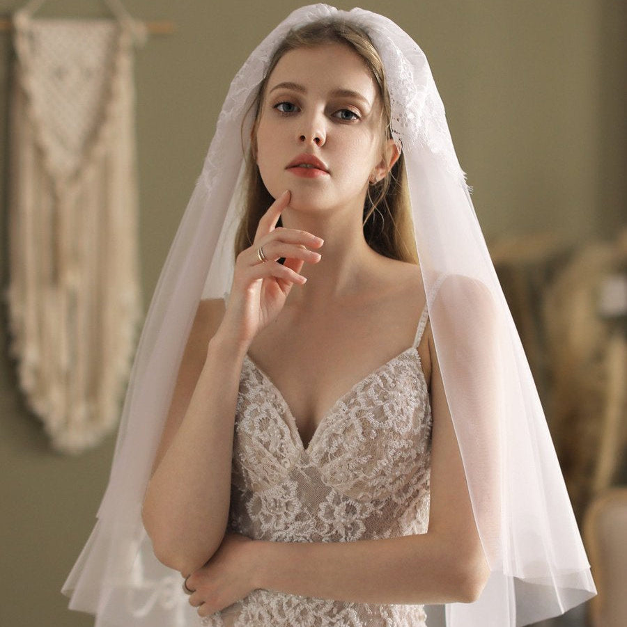 Ivory blusher veil with lace-trimmed edge, draped over head and shoulders