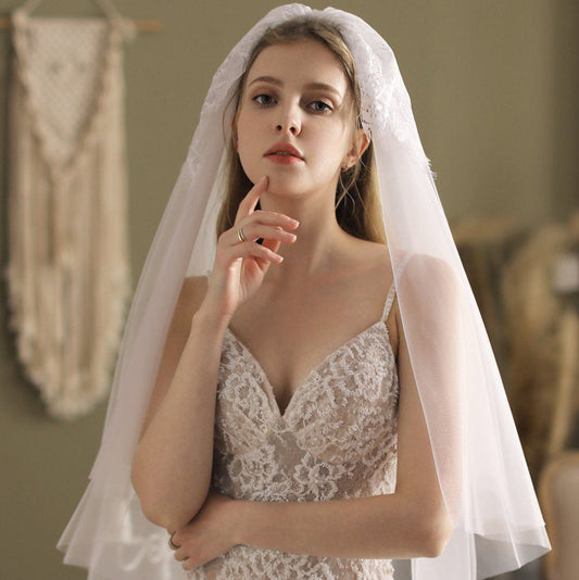 Ivory blusher veil with lace-trimmed edge, draped over head and shoulders