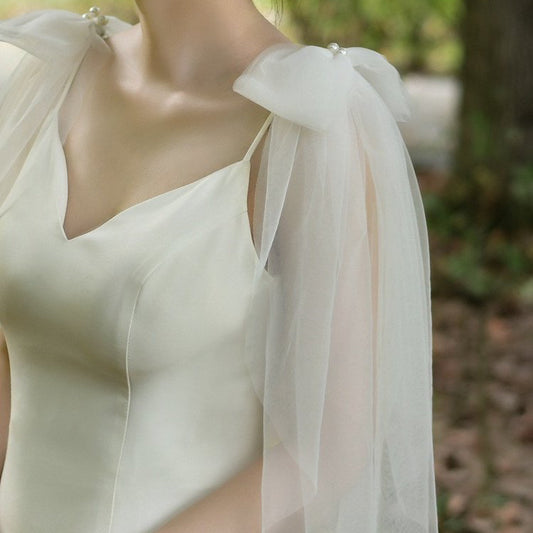 Ivory wedding dress with draped tulle sleeve bows and pearl detail at the neckline