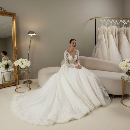 White lace wedding gown with long illusion sleeves, fitted bodice, and flared skirt