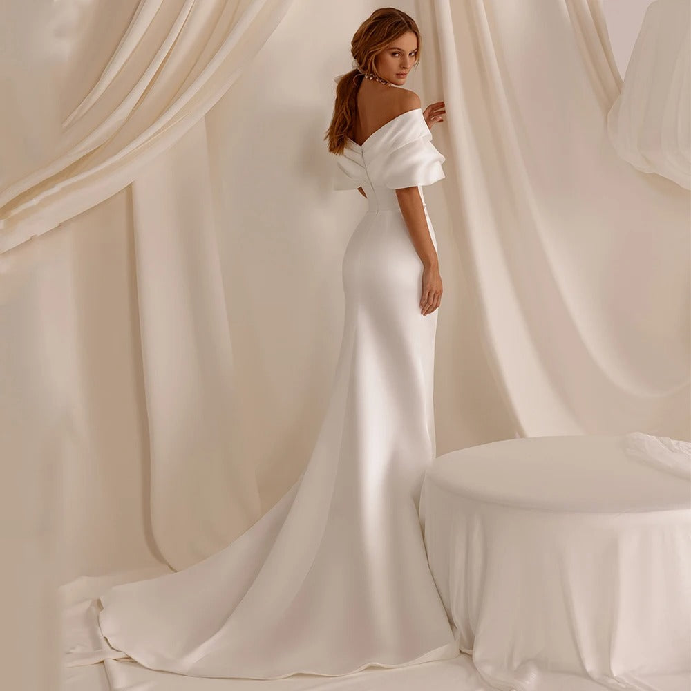 White satin mermaid wedding dress with off-shoulder neckline and flowing train