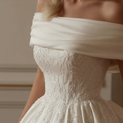 Off-shoulder beaded bodice with sparkling accents on an off-white satin gown