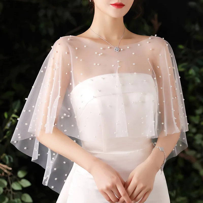 Ivory beaded bridal cape shrug with elbow-length sheer sleeves and pearl-studded neckline