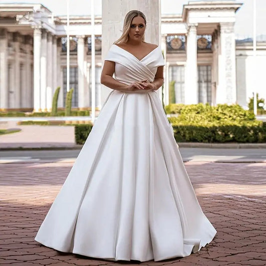 White off-shoulder satin wedding dress with wrapped V neckline and full A-line skirt