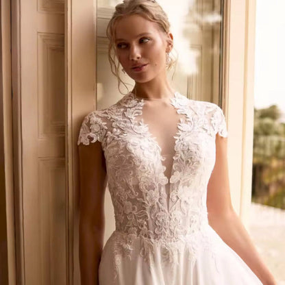Ivory chiffon wedding dress with lace cap sleeves and fitted bodice, pleated skirt