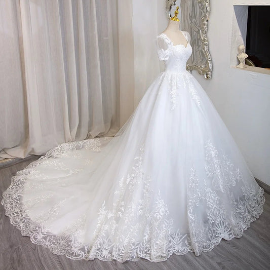 Ivory beaded lace bridal gown with short sleeves, full skirt, and lace hem detailing