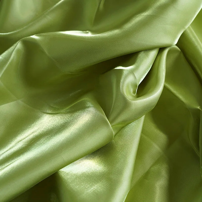 Glossy satin fabric swatch in light green with soft folds and reflective sheen