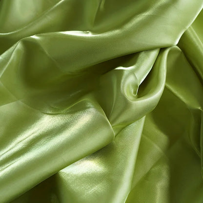Glossy satin fabric swatch in light green with soft folds and reflective sheen