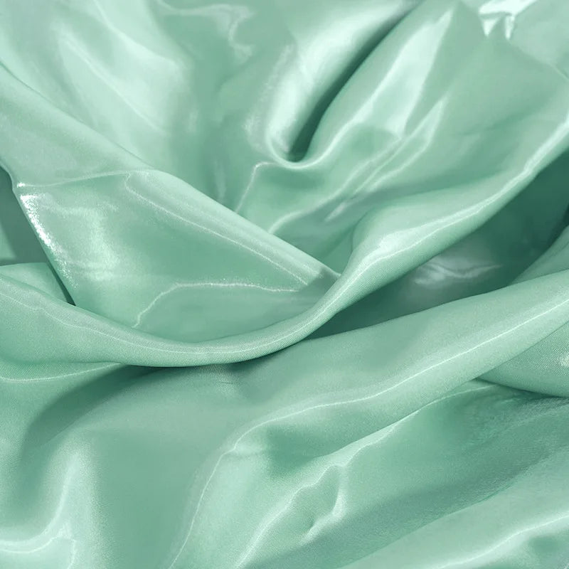 Light mint glossy satin fabric close-up with flowing folds and bright sheen
