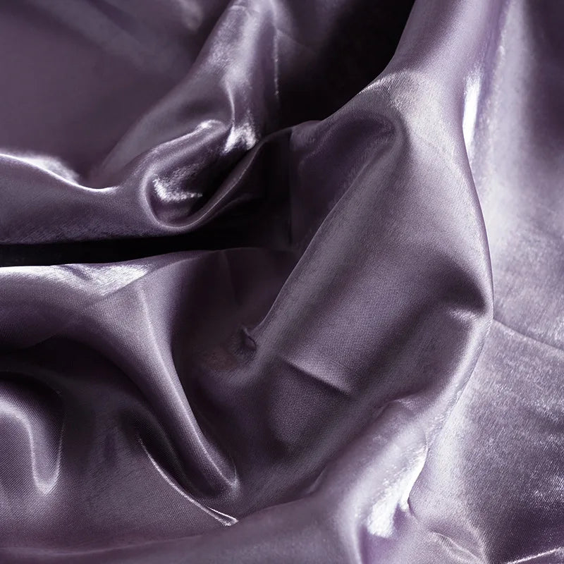 Purple glossy satin fabric close-up with rich sheen and creased folds