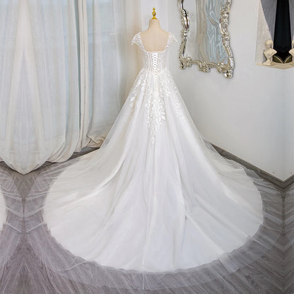 Ivory lace wedding dress with cap sleeves, corset bodice, cascading tulle skirt