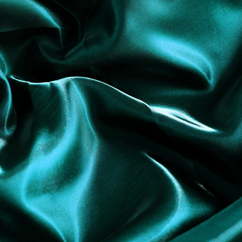 Glossy satin fabric swatch in teal with smooth folds and bright reflective sheen