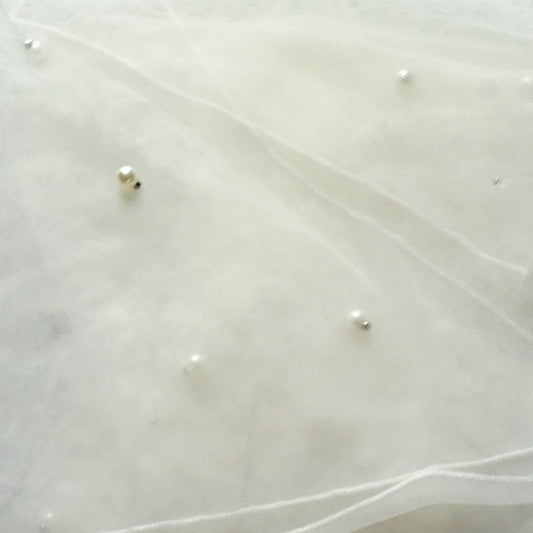 Ivory tulle veil close-up with pearl-like beads and delicate veiling trim
