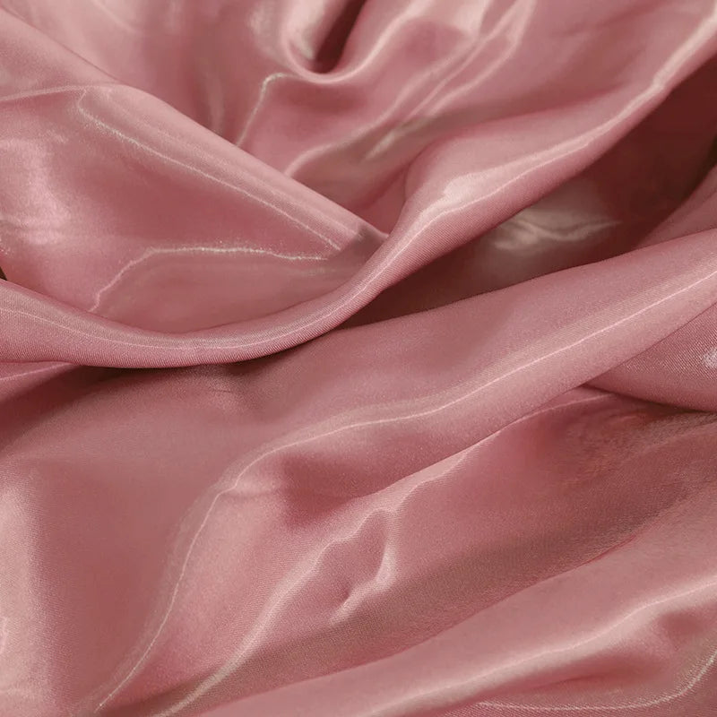 Glossy satin fabric swatch in pale rose with smooth folds and reflective shine
