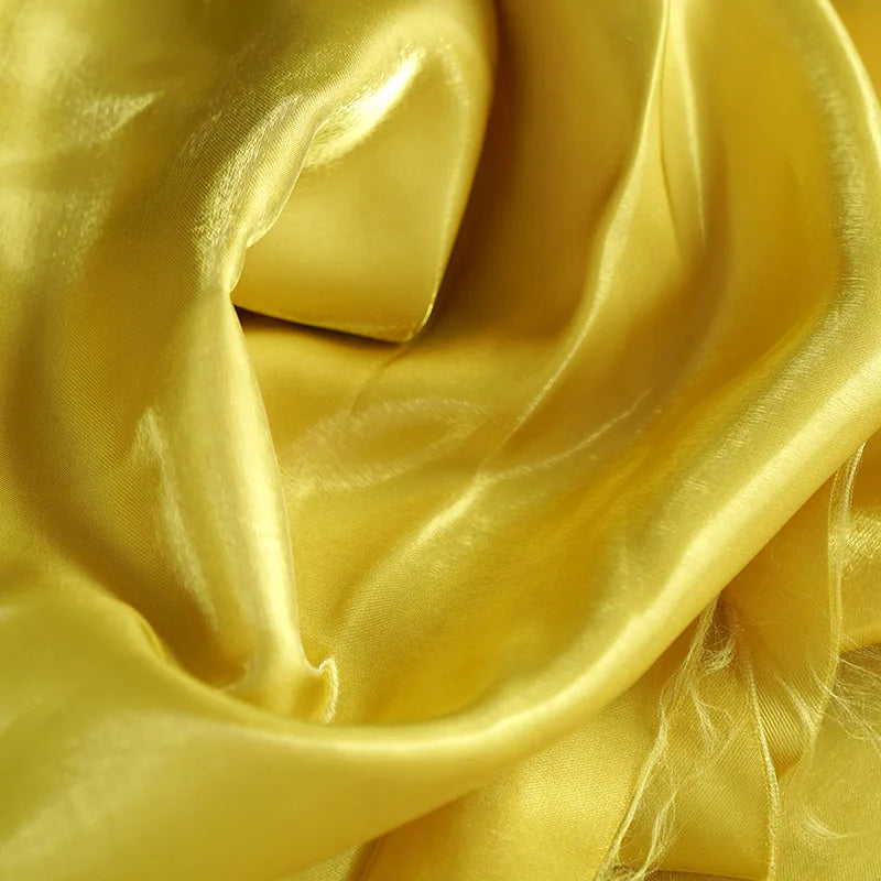 Gold glossy satin fabric close-up with smooth sheen and flowing folds
