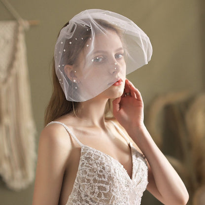 Ivory birdcage veil headpiece with pearl dots across sheer tulle front