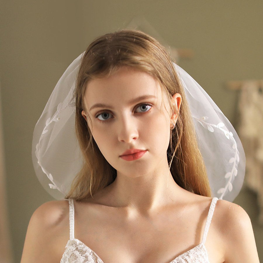 Ivory short wedding veil with lace edge and leaf appliqué framing the face
