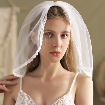 White short bridal veil with scalloped lace edge, draped over head and sides