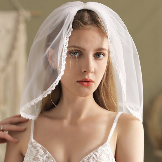 White short bridal veil with scalloped lace edge, draped over head and sides