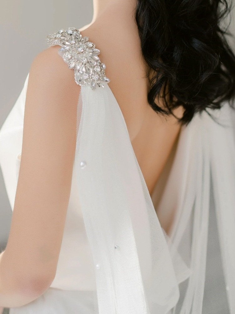 White bridal shoulder veil with crystal-and-pearl applique on upper back strap