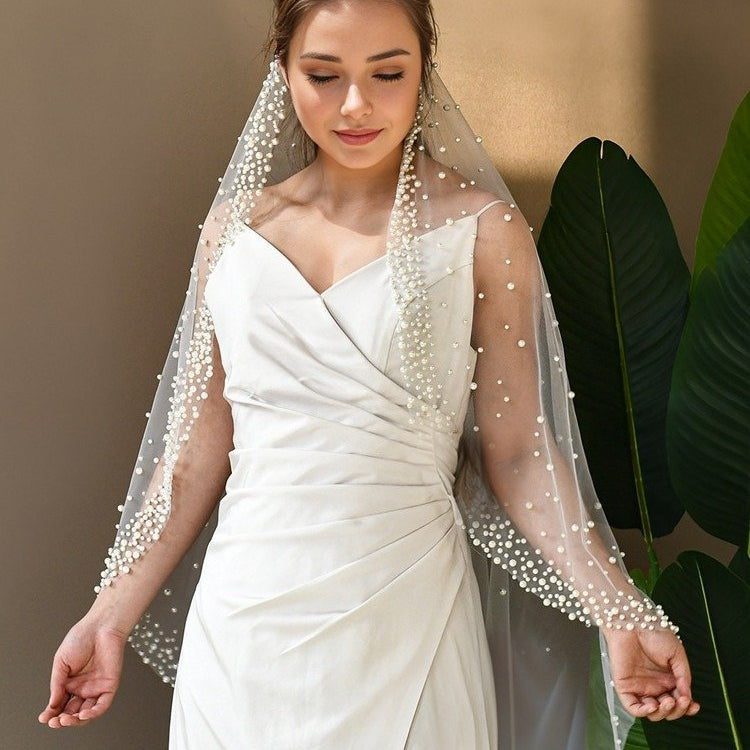 White tulle bridal veil with pearl-beaded border and draped single-layer style