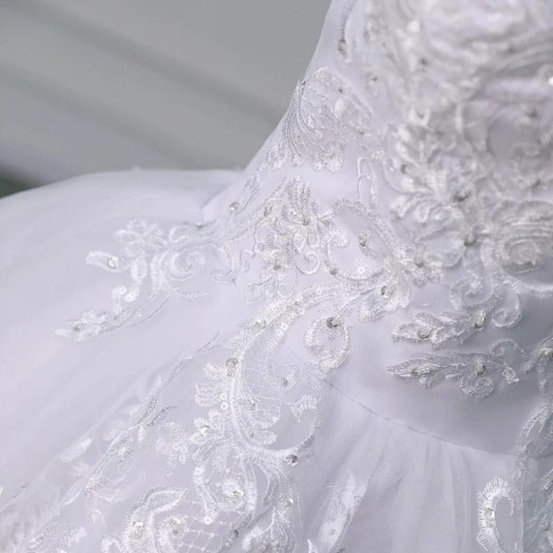 Close-up of white lace bodice with floral embroidery and textured fabric on the skirt