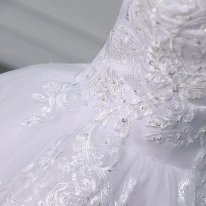 Close-up of white lace bodice with floral embroidery and textured fabric on the skirt