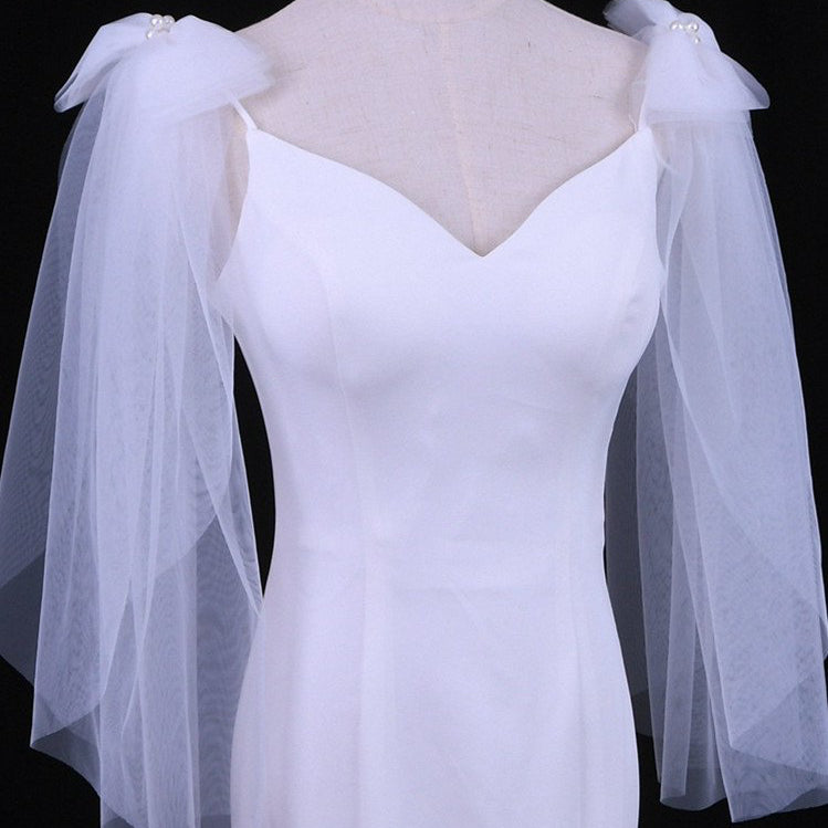 White wedding dress with V-neck bodice, sheer sleeves, and pearl-trim shoulder bows