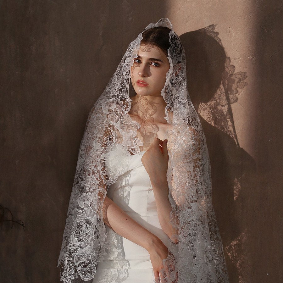 Ivory wedding veil with lace floral overlay draped over shoulders, scalloped trim