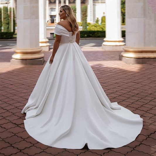 White off-shoulder satin wedding dress with corset-style bodice, fitted waist, A-line skirt